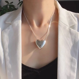 Detail of silver heart pendant necklace on model with elegant lighting and minimal style