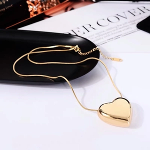Elegant gold heart pendant necklace with snake chain on aesthetic editorial background