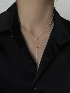 Elegant gold double-layered titanium necklace with beads on a black satin background