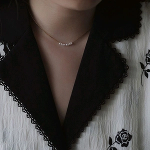 Collana in acciaio al titanio placcato oro 18K con perle bianche su una modella