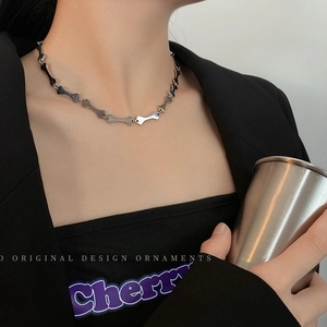 Macro shot of silver bone-shaped links on a stainless steel necklace worn by a model