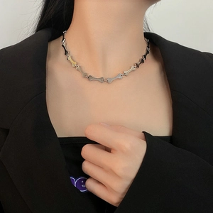 Close-up of titanium steel bone-shaped choker necklace on model wearing black suit