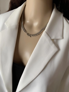 Detail of silver chunky Cuban chain necklace with decorative OT toggle clasp on a model