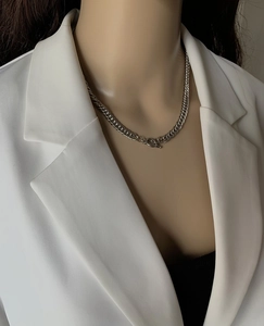 Detail of silver titanium chain necklace with OT toggle clasp on model wearing white blazer