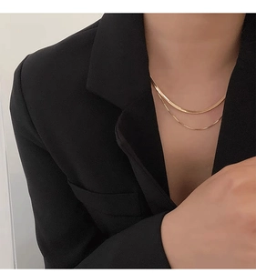 Double-layered gold necklace with flat snake chain and thin box chain on black blazer