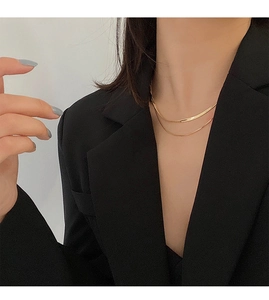 Close-up of double-layer gold necklace with flat snake chain and delicate link chain