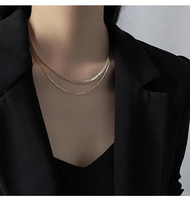 Close-up of double-layer gold snake and bead necklace worn on neck over black blazer