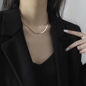 Double-layered gold necklace with flat snake chain and beaded strand on neck