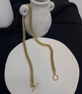 Golden titanium steel chunky chain necklace with OT buckle on a minimalist background