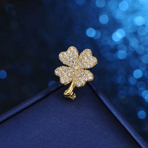 Elegante spilla a quadrifoglio dorata con cristalli scintillanti su velluto blu scuro
