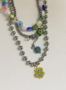 Détails de gros plan des breloques fleurs en verre coloré et du collier à perles argent