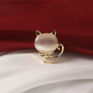 Élégante broche chat dorée avec pierre œil-de-chat et strass sur fond de soie