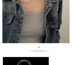 Close-up of a layered silver stainless steel necklace on denim jacket and grey top