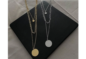 Detail of multi-layered gold and silver necklaces with paperclip chains and round coins