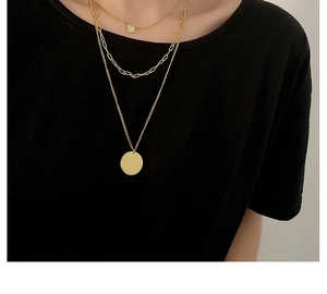 Close-up of three-layer gold layered necklace with round pendants on black shirt