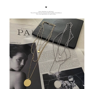 Detailed flatlay of layered gold and silver mixed metal necklaces with circular pendants