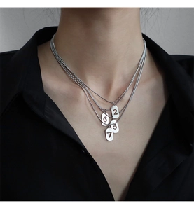 Gros plan d'un collier argenté à plusieurs rangs avec des pendentifs aux chiffres découpés