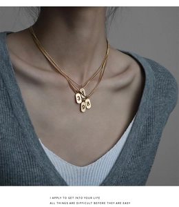 Vue détaillée du collier triple chaîne serpent dorée avec quatre pendentifs numérotés