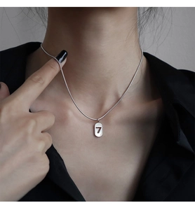 Gros plan d'un collier chaîne serpent en argent avec pendentif ovale chiffre 7
