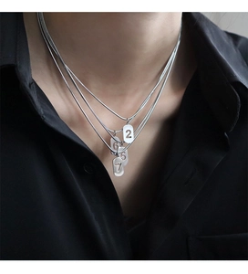 Gros plan sur un collier triple couche avec chiffres porte-bonheur et pendentifs gravés
