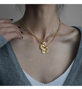 Gros plan de colliers multicouches dorés avec pendentifs chiffres porte-bonheur sur mannequin
