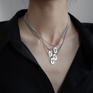 Vue macro d'une chaîne serpent multicouche avec pendentifs chiffres 2 5 6 7 en finition argent