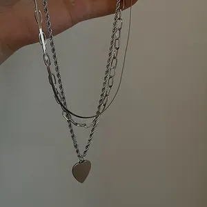 Detail of layered silver heart pendant necklace with square box and snake chain links