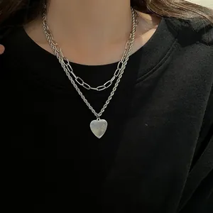 Detail of layered silver heart pendant necklace on model with black sweatshirt