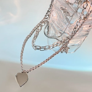 Macro detail of layered silver titanium steel necklace with polished heart pendant