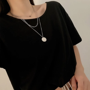 Elegant multi-layered silver necklace with circular pendants on a black minimalist top