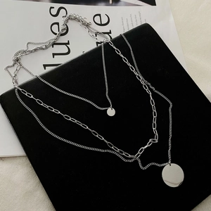 Three-layer silver layered necklace with round pendants on a black display board
