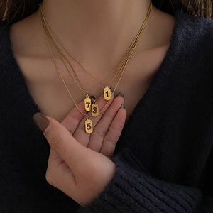 Collier doré multi-rangs avec chiffres porte-bonheur et quatre pendentifs ovales superposés