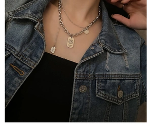 Detail of double-layer silver tiger pendant necklace worn on a blue denim jacket