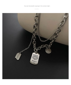 Close-up of double-layered steel chain with engraved tiger head pendant and Brave text