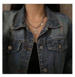 Close-up of double-layer stainless steel necklace with tiger tag pendant on denim jacket