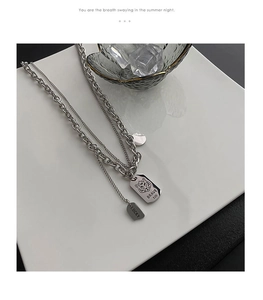Detail of silver double-layered chain necklace with tiger pendant and brave engraving