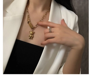 Gros plan d'un collier pendentif ours doré sur un mannequin en veste de costume blanc
