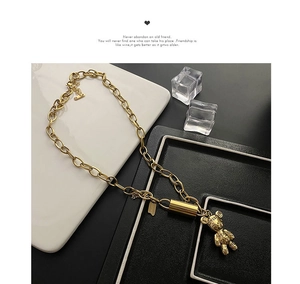 Détail d'un collier à grosse chaîne dorée avec pendentif ours gravé LOVE et PEACE
