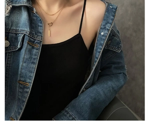 Vue macro d'un collier doré à deux rangs avec pendentif géométrique sur la clavicule