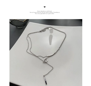 Gros plan du collier à pendentif lettre D argenté superposé sur un plateau céramique