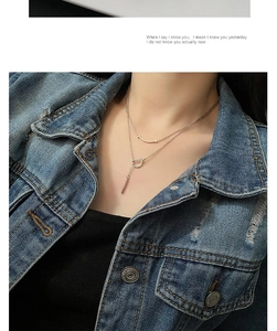 Détail d'un collier superposé en or rose avec pendentifs sourire et lettre D