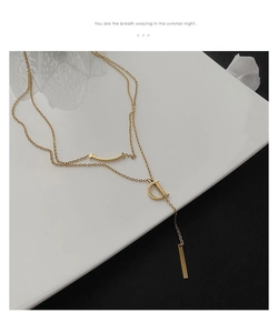 Vue détaillée d'un collier doré multicouche avec barre sourire et pendentif lettre D
