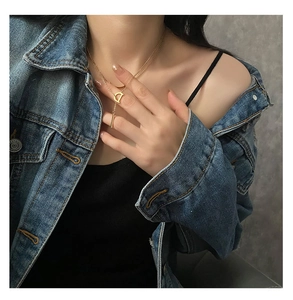 Gros plan du collier avec pendentif lettre D dorée sur un mannequin en veste en jean