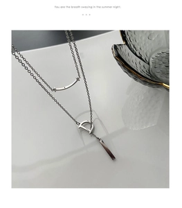 Détail d'un collier argenté multicouche avec pendentif sourire et breloque lettre D