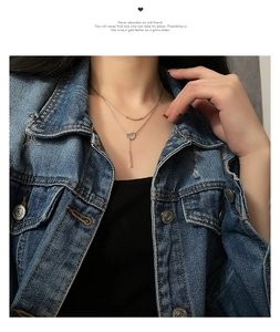Gros plan du collier double épaisseur avec pendentif lettre D et pompon barre verticale