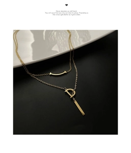 Détail d'un collier doré multicouche avec pendentif lettre D et barre sourire délicate