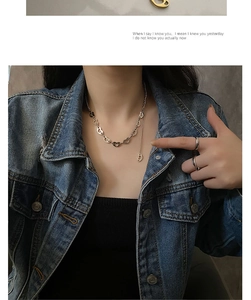Detail of silver heart-shaped chain necklace worn with denim jacket in a cool style