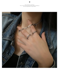 Detail view of heart-shaped link necklace and textured rings worn with denim
