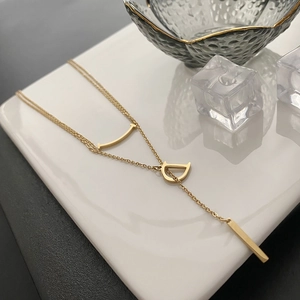 Collier doré avec pendentif lettre D, barre incurvée et barre rectangulaire sur céramique