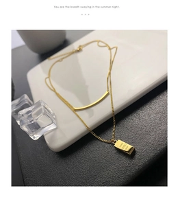 Dettaglio della collana d'oro a due strati con ciondolo rettangolare e incisione